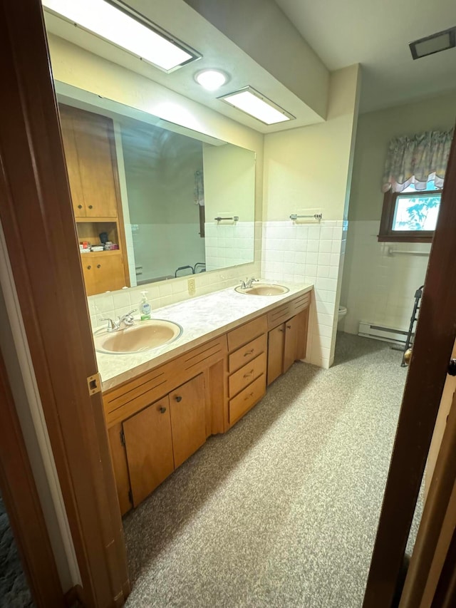 bathroom with tile walls, a baseboard radiator, vanity, and toilet