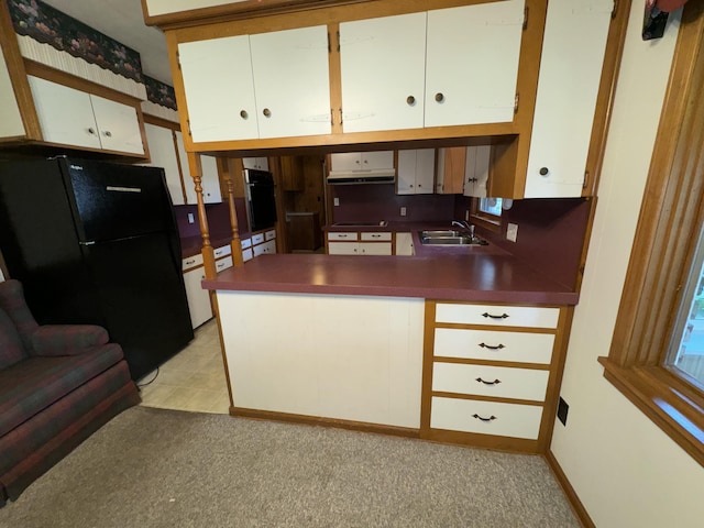 kitchen with freestanding refrigerator, white cabinetry, a sink, and dark countertops