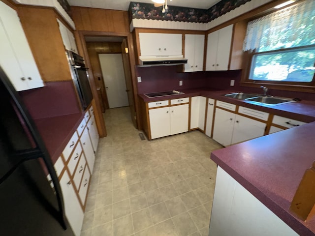 kitchen with black electric stovetop, oven, a sink, exhaust hood, and dark countertops