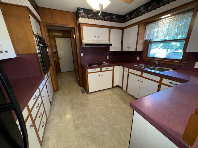 kitchen featuring under cabinet range hood, a sink, white cabinets, black appliances, and dark countertops