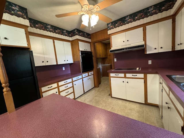 kitchen featuring dark countertops, white cabinets, under cabinet range hood, and black appliances