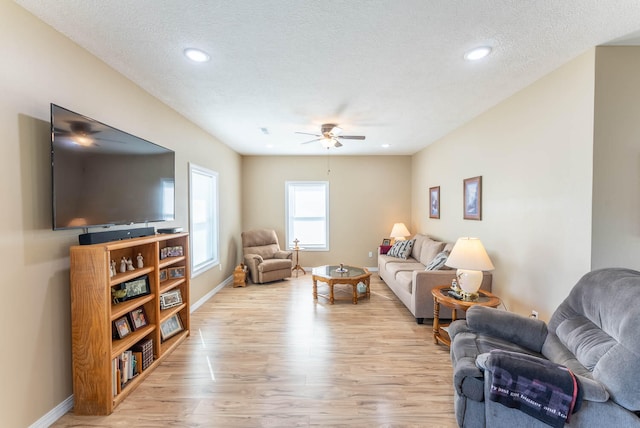 living room featuring light hardwood / wood-style floors, a textured ceiling, and ceiling fan