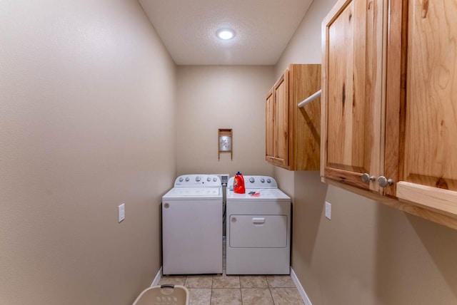 clothes washing area with light tile patterned flooring, washer and dryer, cabinets, and a textured ceiling