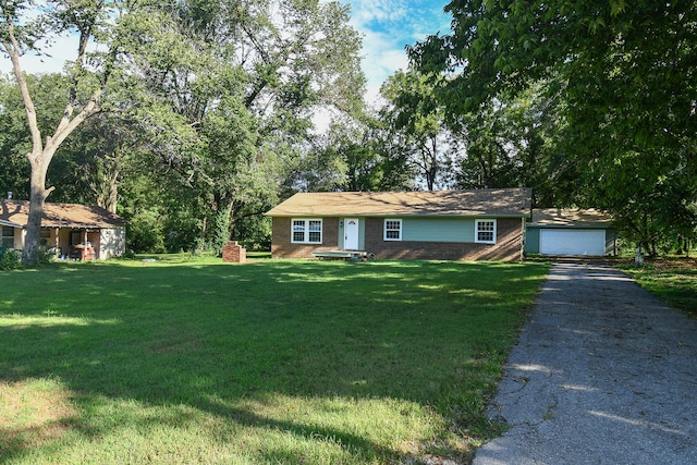 single story home featuring a garage, an outbuilding, and a front yard