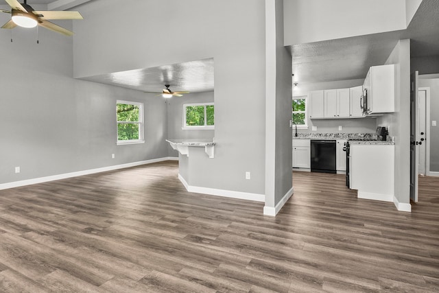 unfurnished living room with ceiling fan, dark hardwood / wood-style flooring, and a textured ceiling