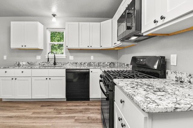 kitchen featuring black appliances, light hardwood / wood-style floors, and white cabinets