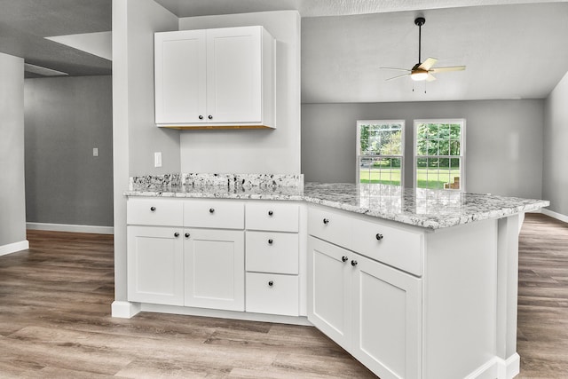 kitchen featuring kitchen peninsula, white cabinetry, light hardwood / wood-style floors, and a textured ceiling