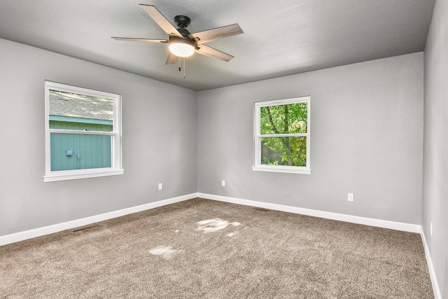 empty room with carpet flooring, ceiling fan, and a textured ceiling