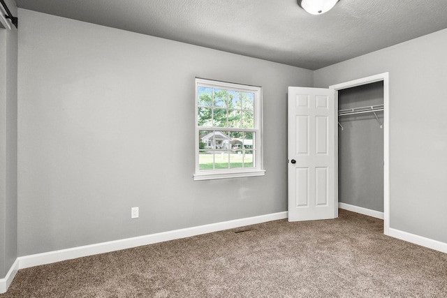 unfurnished bedroom with carpet flooring, a textured ceiling, and a closet