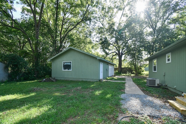 view of yard featuring an outbuilding, central AC, and a garage