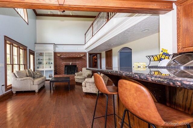 bar featuring dark wood-type flooring, a fireplace, and a towering ceiling