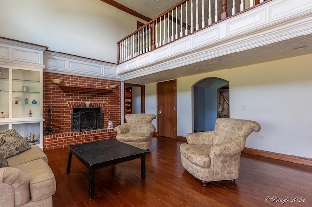 living area featuring hardwood / wood-style floors, stairs, arched walkways, baseboards, and a brick fireplace