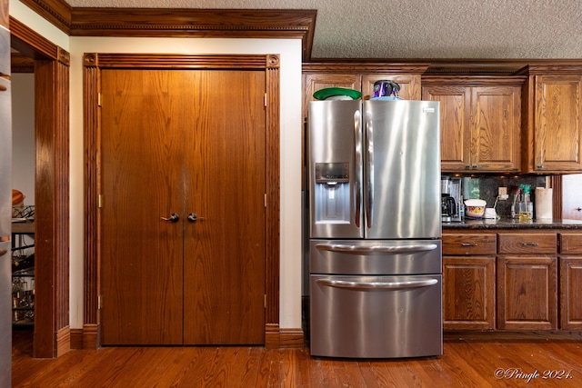 kitchen featuring brown cabinetry, stainless steel refrigerator with ice dispenser, a textured ceiling, and dark wood-style floors