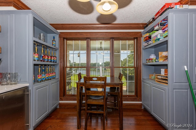 dining room featuring ornamental molding, a dry bar, a textured ceiling, and dark wood-style floors