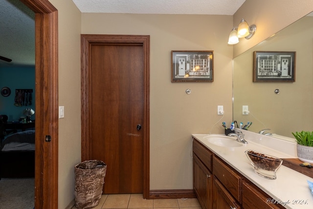 ensuite bathroom with a textured ceiling, tile patterned flooring, vanity, and ensuite bathroom