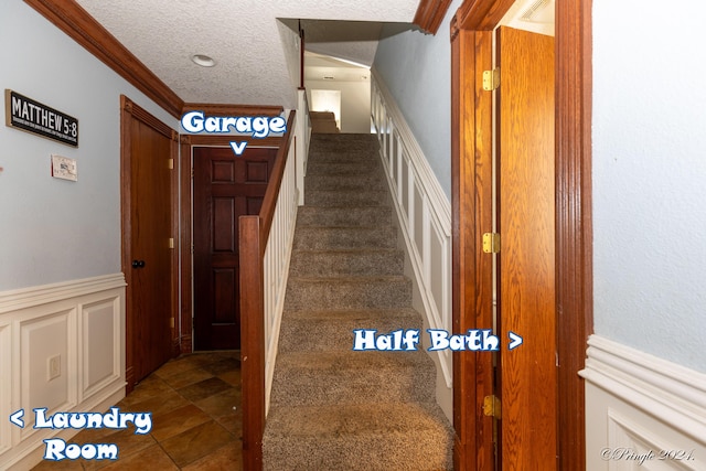 stairway with crown molding, a wainscoted wall, a textured ceiling, and carpet