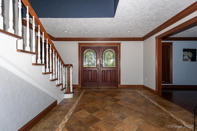 foyer entrance featuring stone finish floor, stairs, crown molding, and baseboards