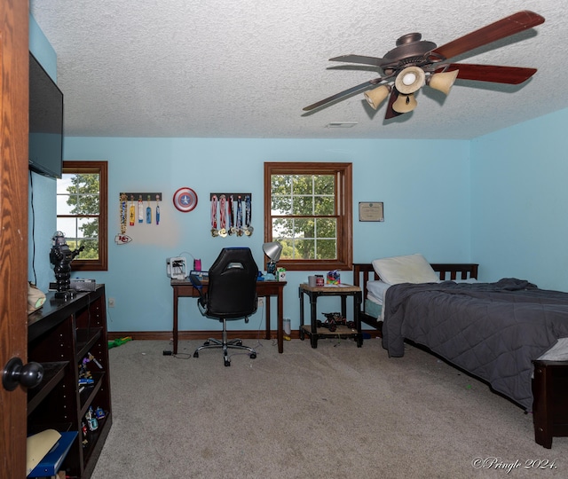 bedroom featuring ceiling fan, a textured ceiling, carpet flooring, and multiple windows