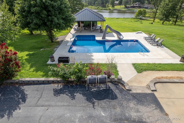 view of pool featuring a fenced in pool, a water view, a water slide, a patio area, and a lawn