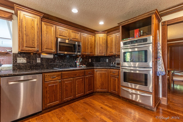 kitchen featuring stainless steel appliances, a textured ceiling, a warming drawer, backsplash, and dark wood-type flooring