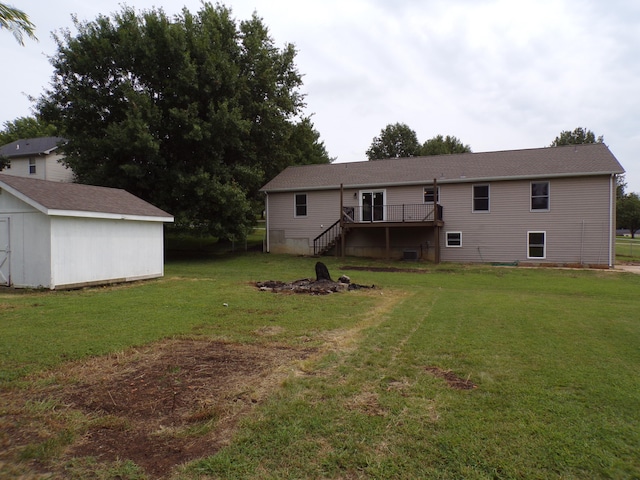 rear view of property featuring stairs, a yard, an outdoor structure, and a wooden deck