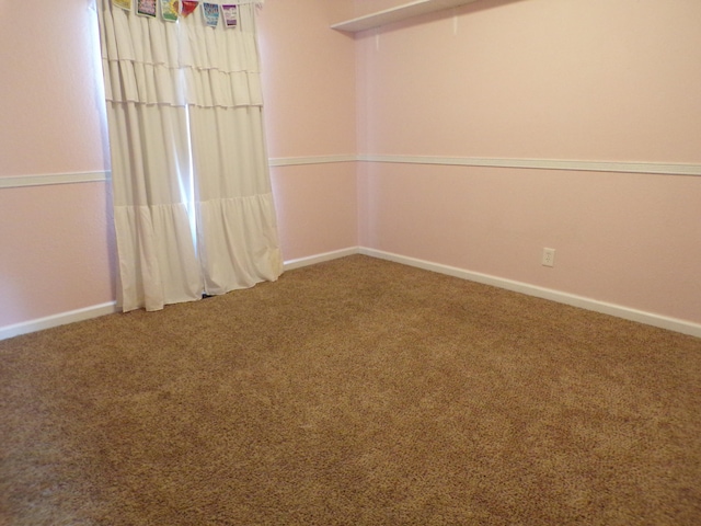 unfurnished room with attic access, carpet flooring, and baseboards