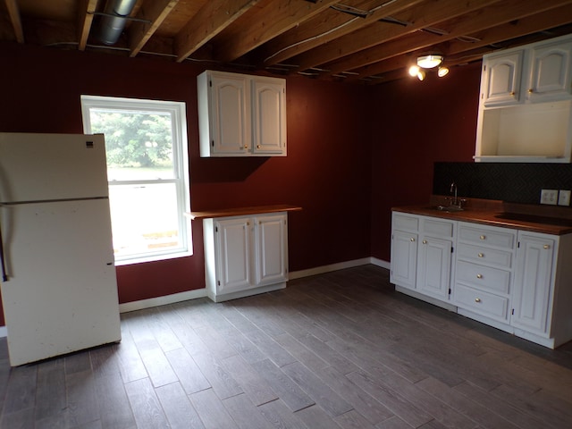 kitchen featuring dark wood-type flooring, freestanding refrigerator, white cabinets, and a sink