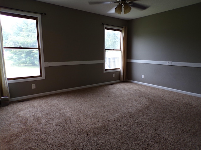 carpeted empty room with a ceiling fan, visible vents, and baseboards