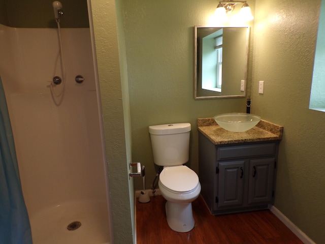 full bathroom with toilet, a stall shower, vanity, wood finished floors, and baseboards