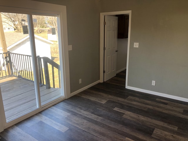 spare room with baseboards and dark wood finished floors