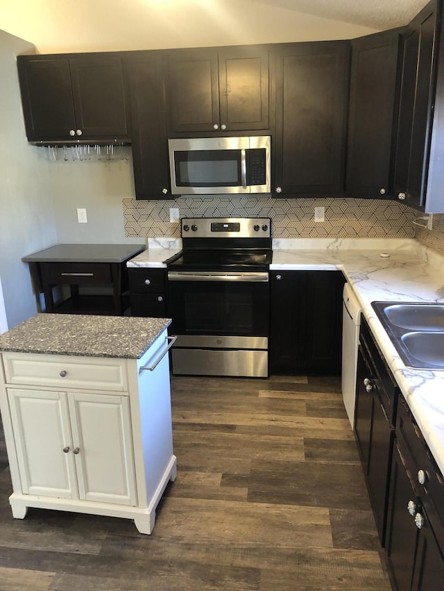 kitchen with decorative backsplash, dark wood-style flooring, light stone countertops, stainless steel appliances, and a sink