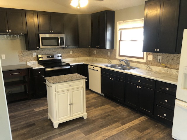 kitchen featuring dark wood-style flooring, a sink, appliances with stainless steel finishes, backsplash, and a center island