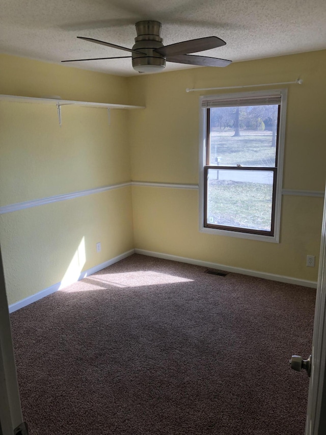 carpeted spare room featuring a ceiling fan, baseboards, visible vents, and a textured ceiling