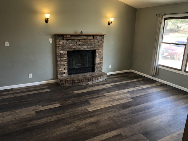 unfurnished living room featuring a brick fireplace, wood finished floors, and baseboards