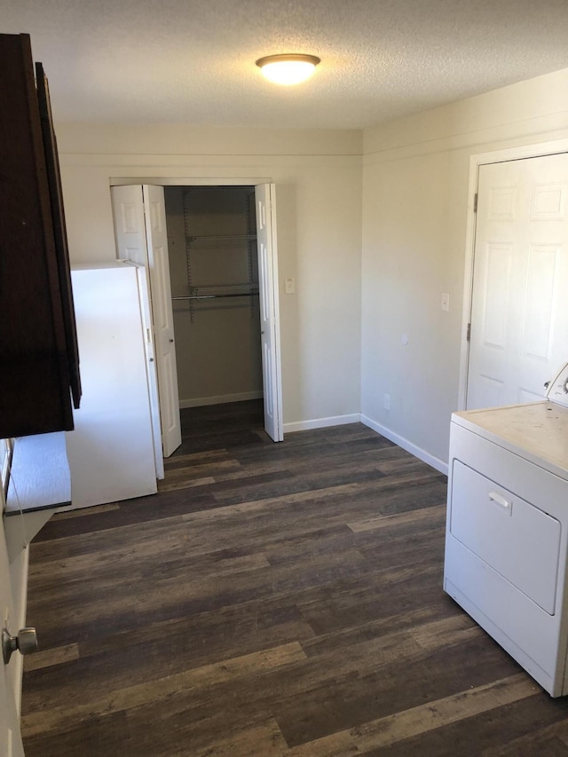 interior space with baseboards, washer / clothes dryer, dark wood finished floors, and a textured ceiling