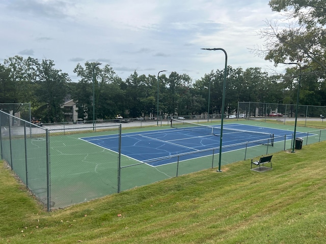 view of tennis court featuring a yard