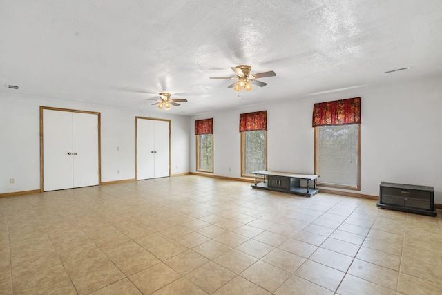 empty room with light tile patterned floors, a textured ceiling, and ceiling fan