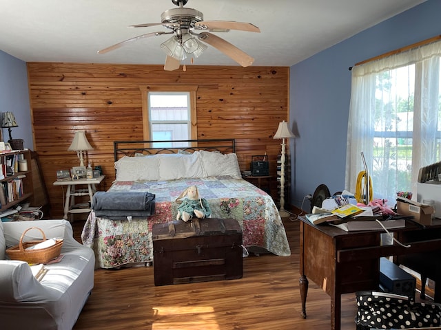 bedroom with wood walls, hardwood / wood-style floors, and ceiling fan