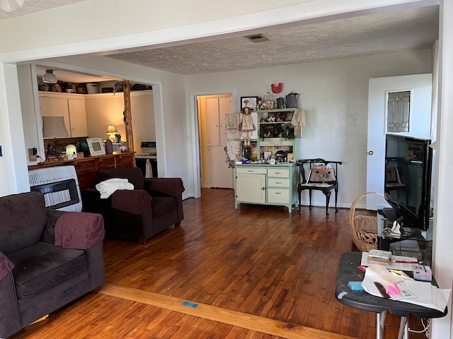 living room with wood-type flooring, heating unit, and a textured ceiling