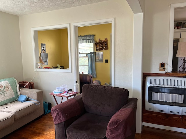 living room featuring wood-type flooring, heating unit, and a textured ceiling