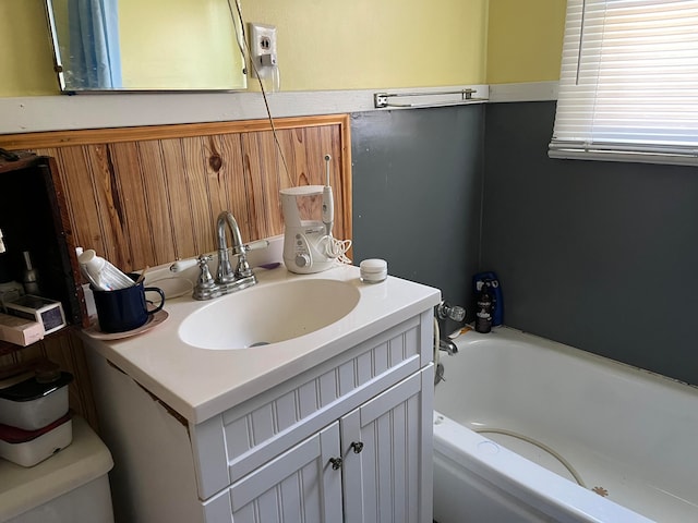 bathroom featuring a washtub, vanity, and toilet