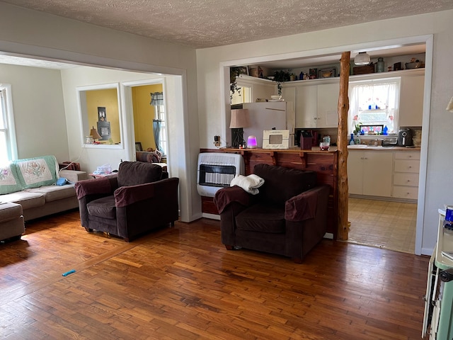 living room with heating unit, hardwood / wood-style flooring, and a textured ceiling