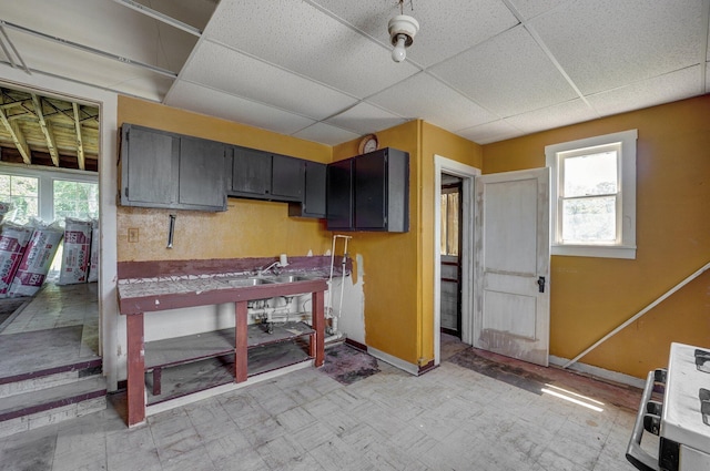 kitchen with a healthy amount of sunlight, a drop ceiling, baseboards, and light floors