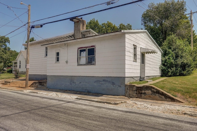 view of side of home featuring a chimney and a yard