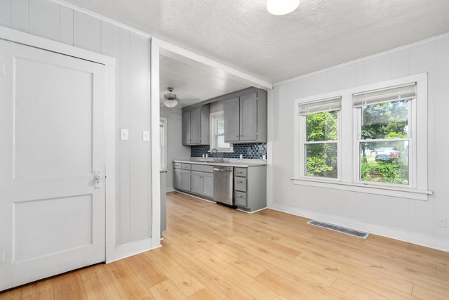 kitchen with light countertops, visible vents, stainless steel dishwasher, decorative backsplash, and gray cabinetry