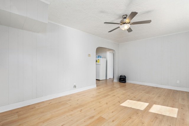 empty room featuring hardwood / wood-style flooring, wooden walls, and ceiling fan