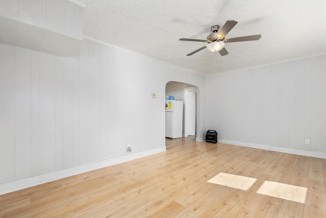 unfurnished room featuring arched walkways, wood finished floors, crown molding, and ceiling fan