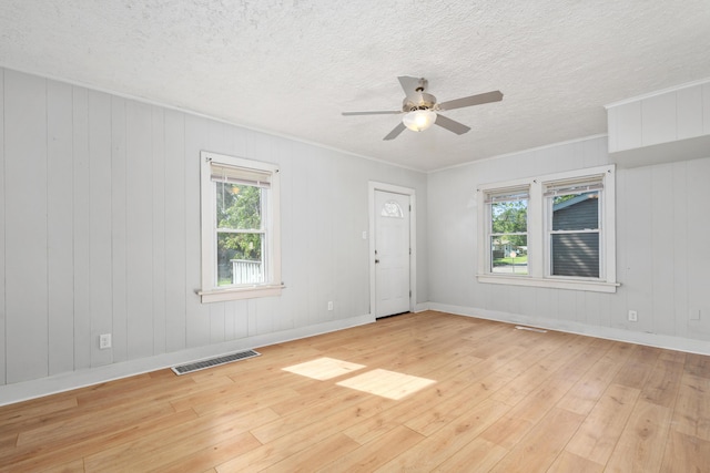 spare room with visible vents, light wood finished floors, a ceiling fan, and a healthy amount of sunlight