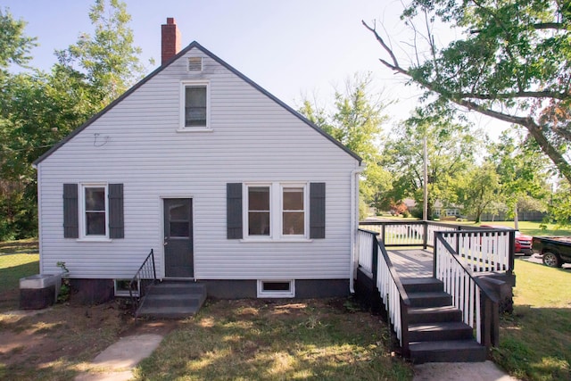 view of front of house with a chimney, a wooden deck, and a front yard