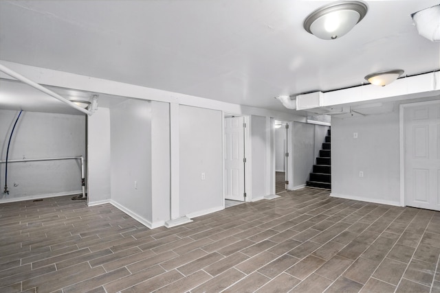 finished basement with baseboards, wood finished floors, and stairway
